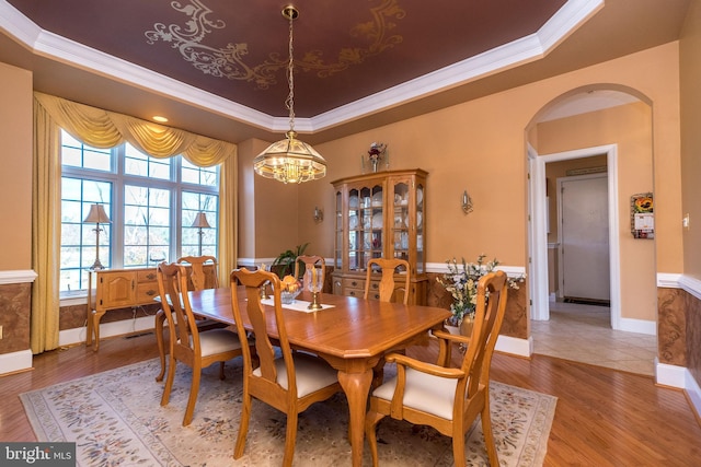 dining area featuring arched walkways, a notable chandelier, crown molding, and a tray ceiling