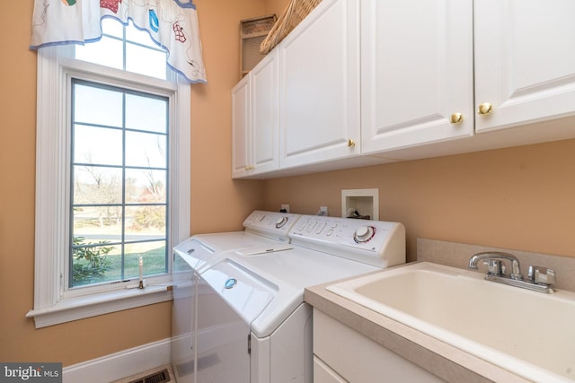 clothes washing area with cabinet space, washer and dryer, and a sink