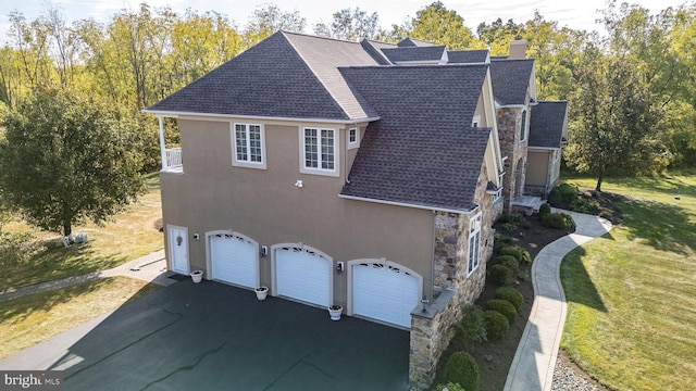 view of property exterior featuring stucco siding, driveway, stone siding, roof with shingles, and an attached garage