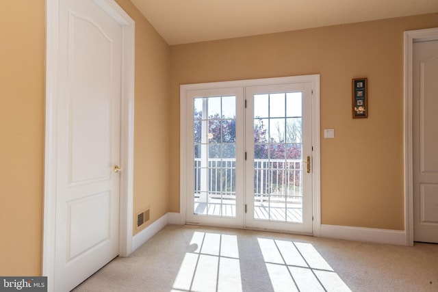 entryway with visible vents, baseboards, and light colored carpet