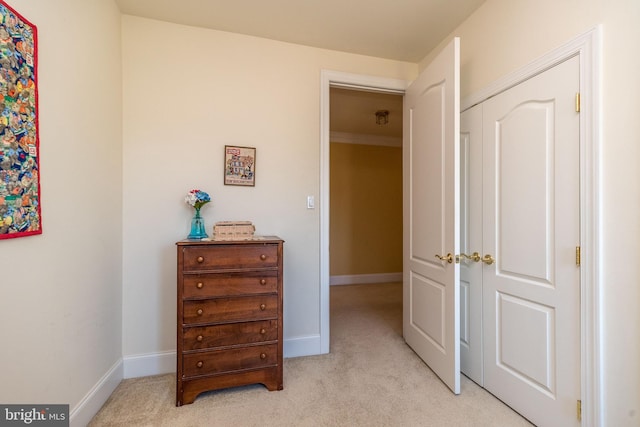 bedroom with a closet, light colored carpet, and baseboards