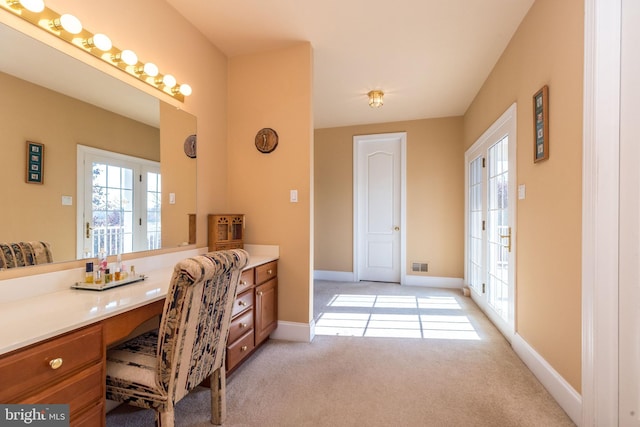 office space with visible vents, baseboards, light colored carpet, and built in study area