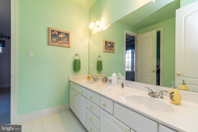 full bathroom with tile patterned flooring, double vanity, baseboards, and a sink