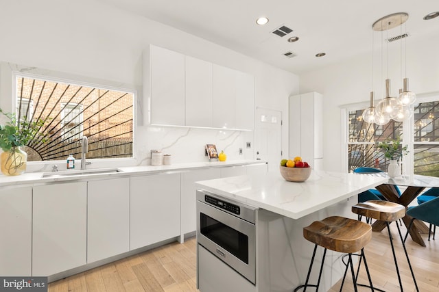 kitchen featuring white cabinetry, a sink, a kitchen bar, and modern cabinets