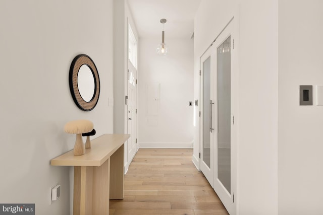 doorway with baseboards and light wood-style floors