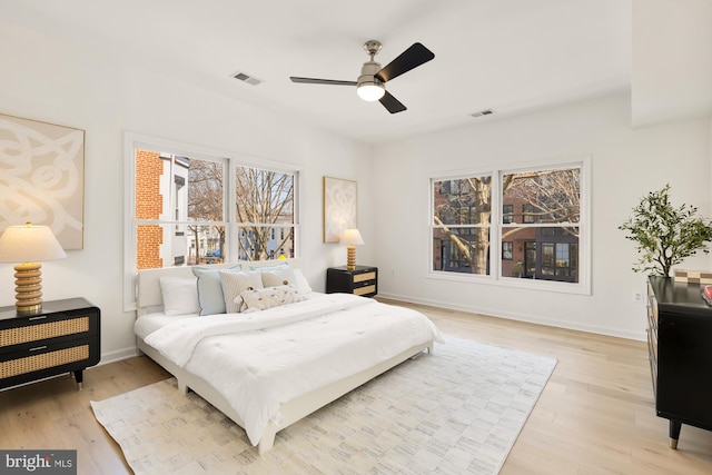 bedroom featuring ceiling fan, light wood-style flooring, visible vents, and baseboards