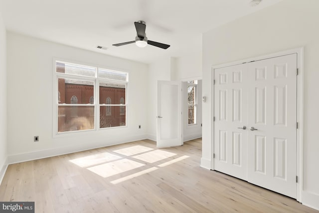 unfurnished bedroom with light wood-style flooring, a ceiling fan, visible vents, baseboards, and a closet