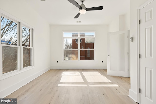 unfurnished bedroom with multiple windows, light wood-style flooring, and baseboards