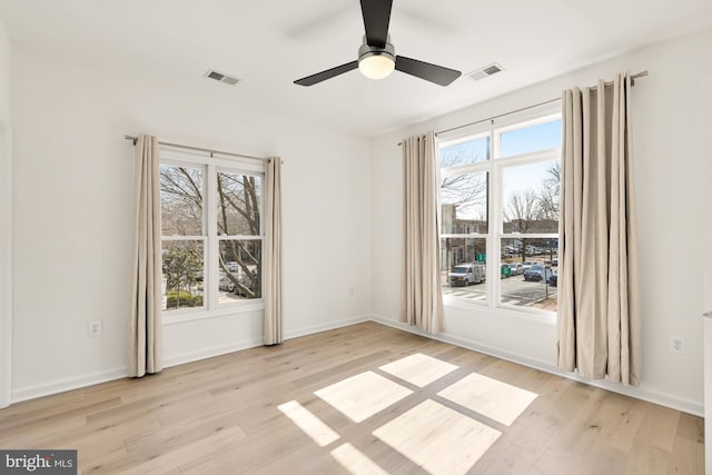 spare room featuring light wood-style flooring, visible vents, and a wealth of natural light