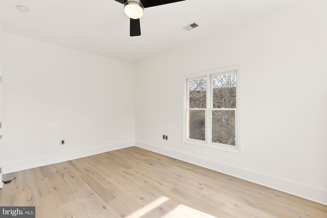 empty room featuring light wood finished floors, baseboards, visible vents, and ceiling fan