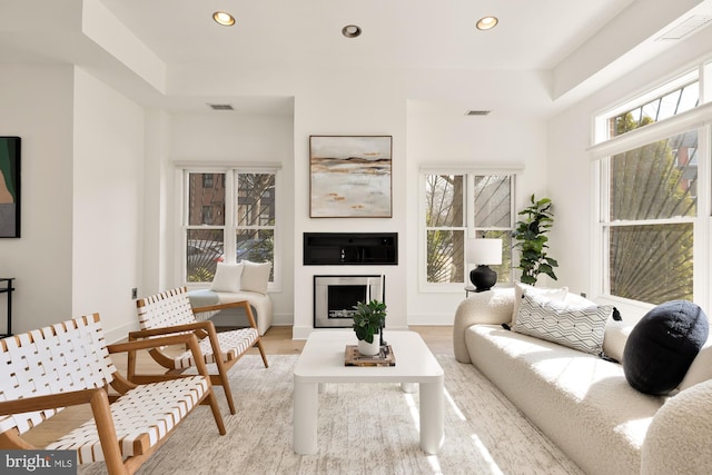 living room featuring light wood-style flooring, a fireplace, visible vents, and recessed lighting