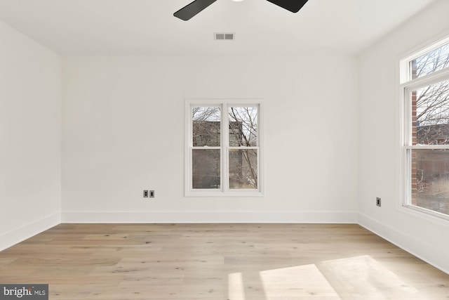 unfurnished room with a healthy amount of sunlight, light wood-style flooring, visible vents, and baseboards