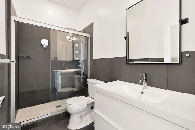 full bath with a stall shower, wainscoting, toilet, vanity, and tile walls