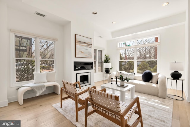 living area featuring light wood-type flooring, a fireplace, visible vents, and recessed lighting