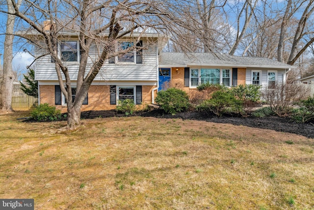 tri-level home with fence, a front lawn, and brick siding