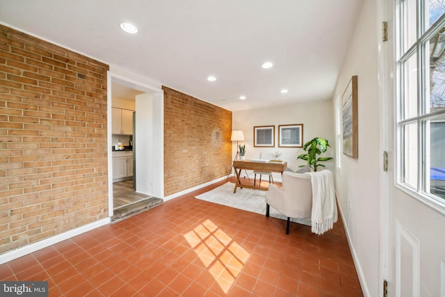 interior space featuring baseboards, brick wall, and recessed lighting