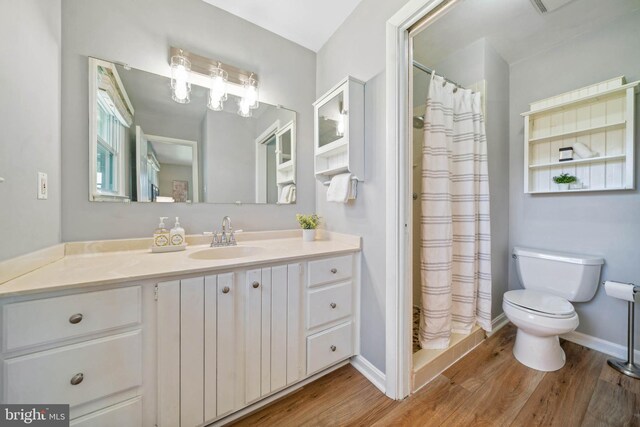 full bathroom featuring vanity, curtained shower, wood finished floors, and toilet