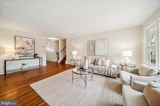 living room featuring stairs, wood finished floors, and baseboards