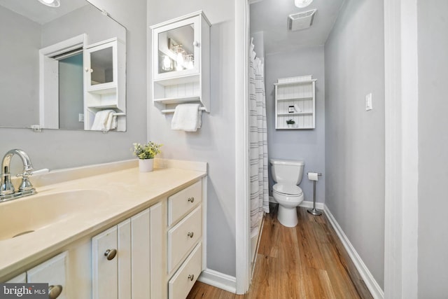 bathroom with toilet, wood finished floors, vanity, visible vents, and baseboards