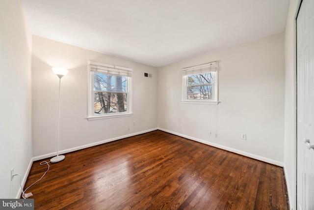 unfurnished bedroom featuring visible vents, multiple windows, baseboards, and wood finished floors