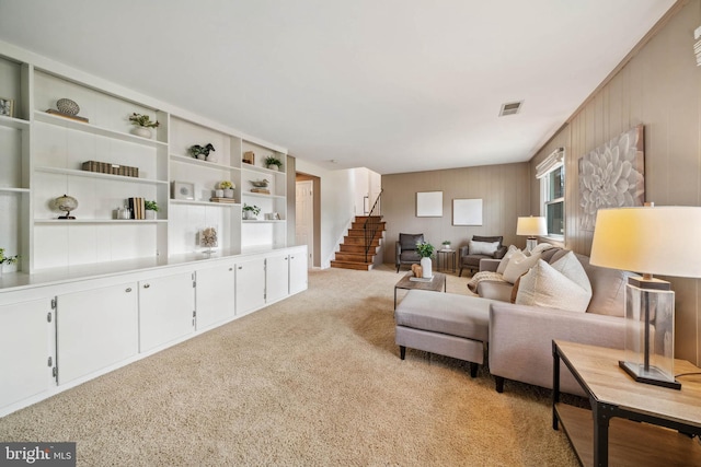 living room featuring light carpet, stairs, and visible vents