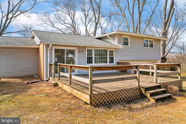 back of property with a deck and roof with shingles