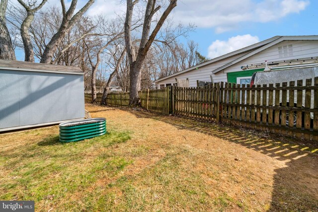 view of yard with a storage unit, fence, and an outbuilding