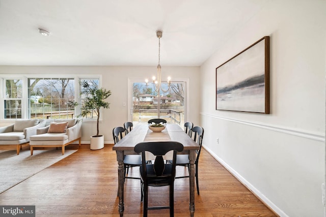 dining area featuring a notable chandelier, baseboards, and wood finished floors