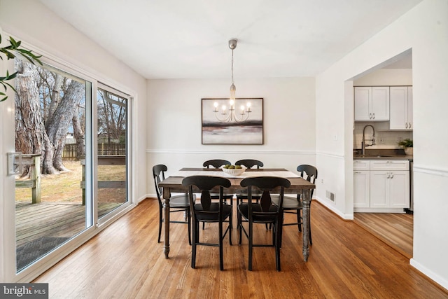 dining space featuring baseboards, an inviting chandelier, and light wood-style floors