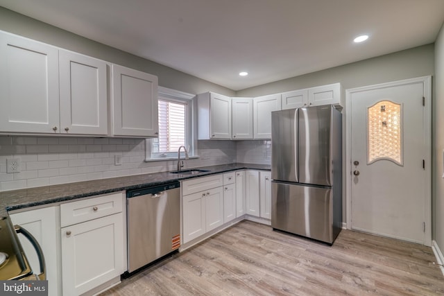 kitchen with light wood finished floors, tasteful backsplash, appliances with stainless steel finishes, white cabinetry, and a sink