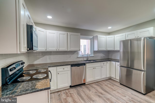 kitchen featuring light wood finished floors, appliances with stainless steel finishes, backsplash, and a sink