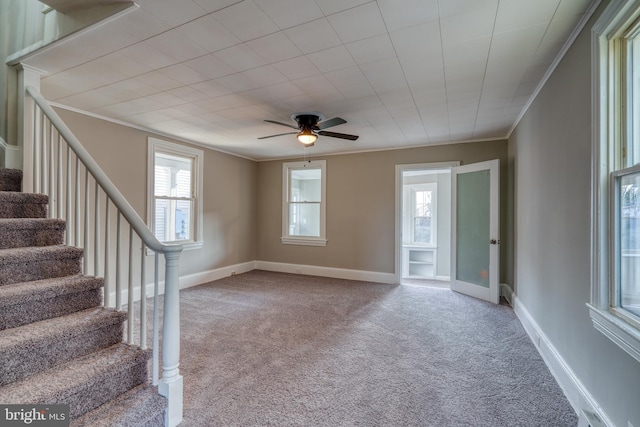 empty room featuring carpet floors, crown molding, and stairs