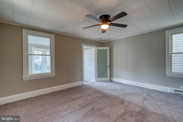 carpeted empty room featuring a ceiling fan, baseboards, and crown molding