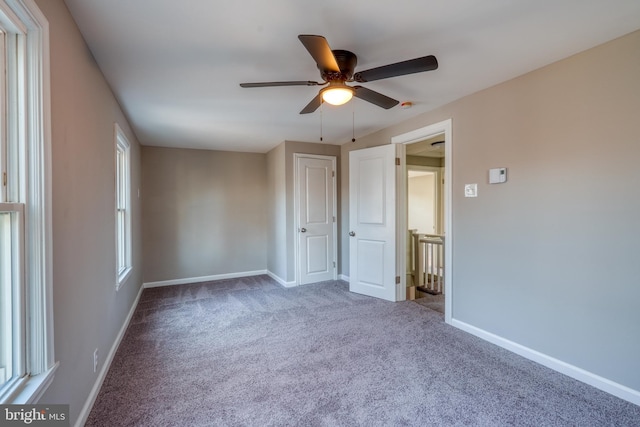 carpeted empty room featuring a ceiling fan and baseboards