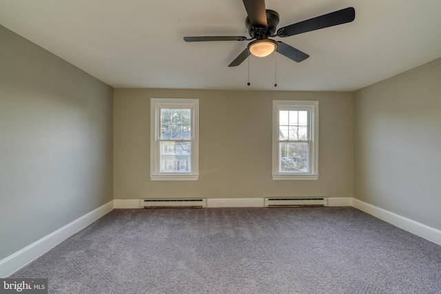 spare room featuring a baseboard heating unit, plenty of natural light, baseboards, and carpet flooring