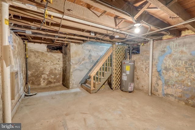 unfinished basement featuring stairway and electric water heater