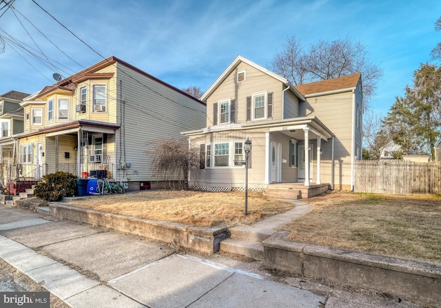 traditional home featuring a porch and fence