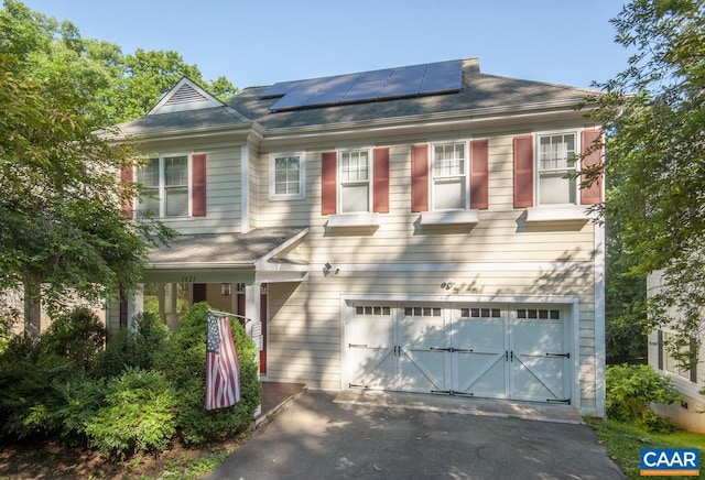 view of front of property featuring a garage, solar panels, and aphalt driveway