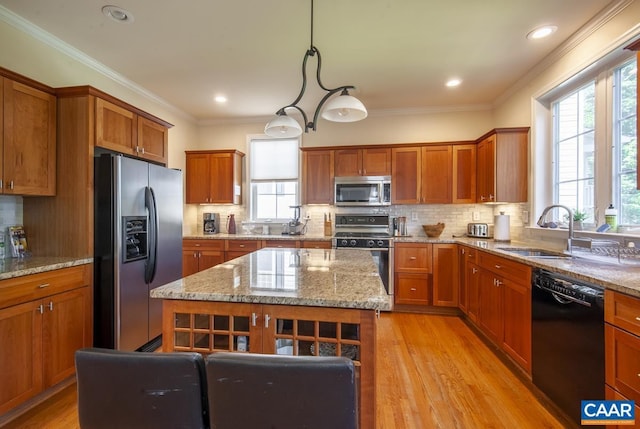 kitchen featuring a sink, light wood-style floors, appliances with stainless steel finishes, brown cabinets, and crown molding