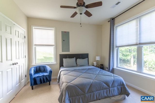 bedroom with electric panel, visible vents, light carpet, and multiple windows