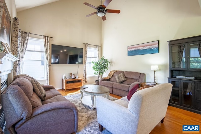 living area with high vaulted ceiling, ceiling fan, and wood finished floors