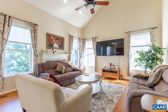 living room featuring light wood-style floors, visible vents, high vaulted ceiling, and ceiling fan