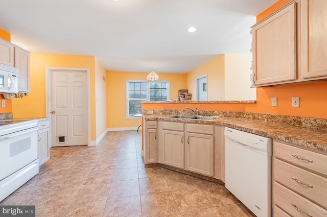 kitchen featuring light brown cabinets, white appliances, a peninsula, and a sink