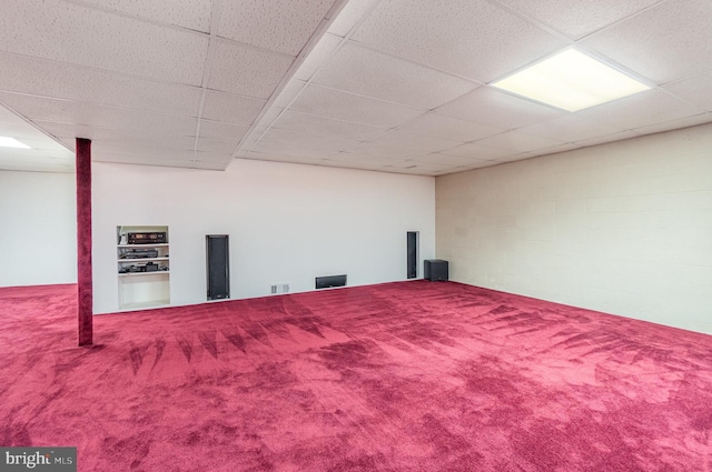 finished below grade area with concrete block wall, a paneled ceiling, visible vents, and carpet floors