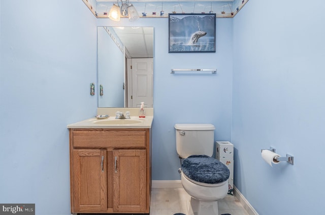 bathroom with toilet, vanity, and baseboards