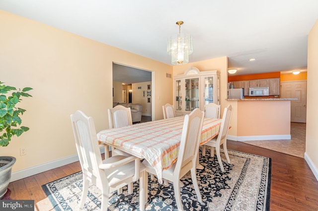 dining space featuring hardwood / wood-style floors, visible vents, baseboards, and a chandelier