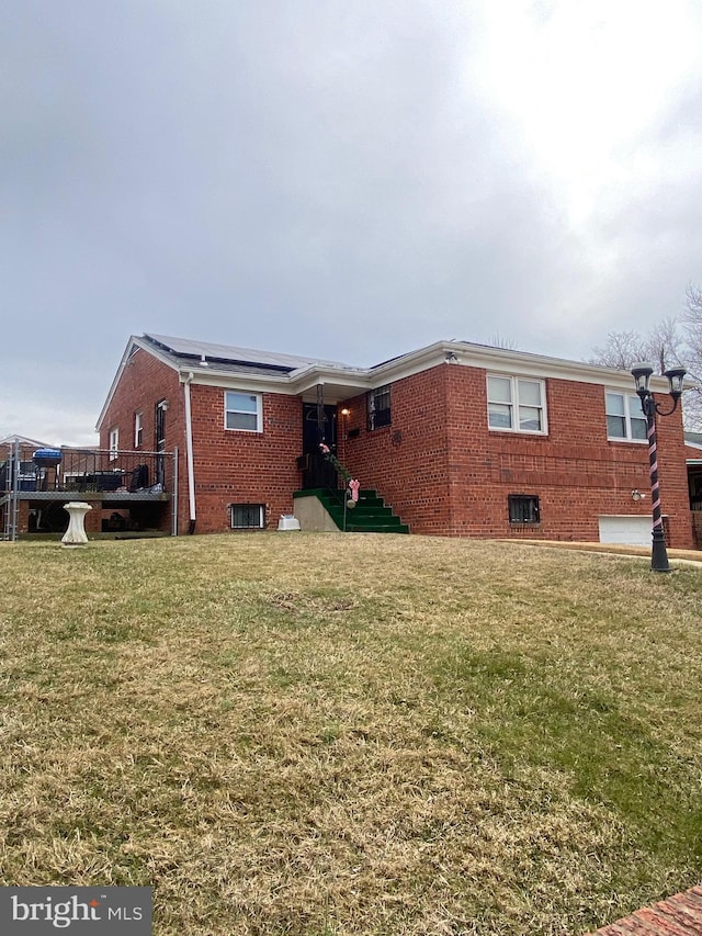 rear view of house with a yard, solar panels, and brick siding