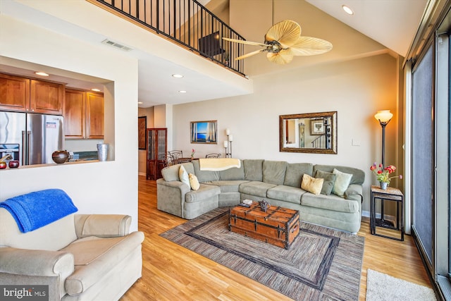 living area featuring light wood finished floors, recessed lighting, ceiling fan, and a high ceiling