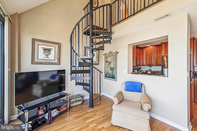 living area featuring stairs, wood finished floors, baseboards, and high vaulted ceiling