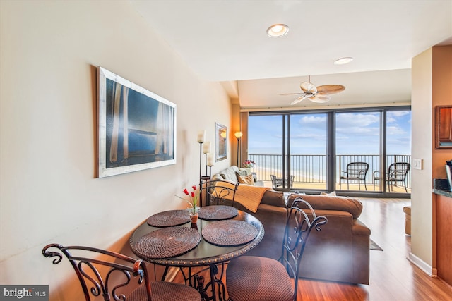 dining space with a ceiling fan, wood finished floors, a water view, and recessed lighting
